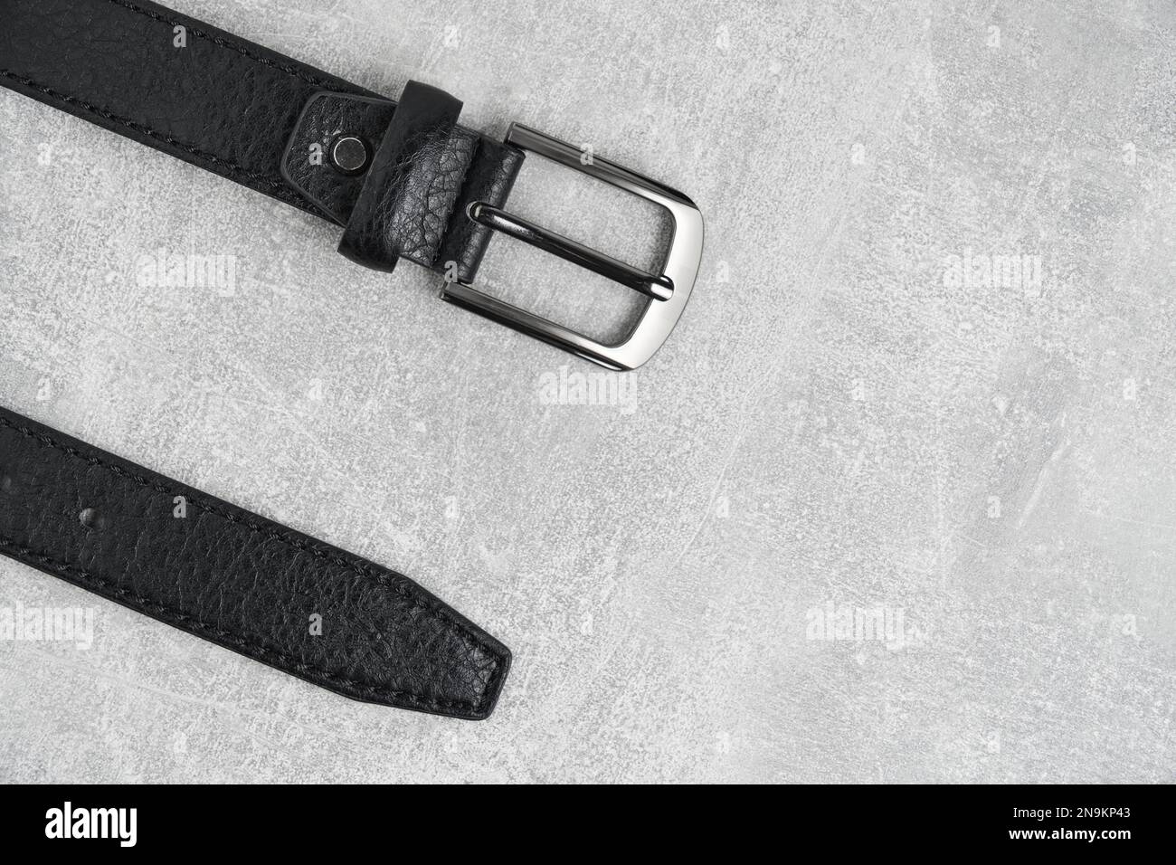 Black men leather belt with metal badge gray concrete background Stock Photo