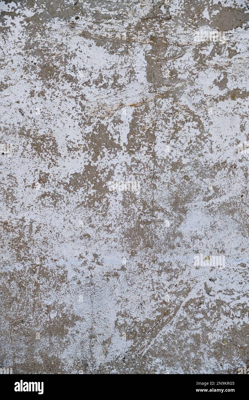 Old, gray concrete wall with peeling white paint Stock Photo