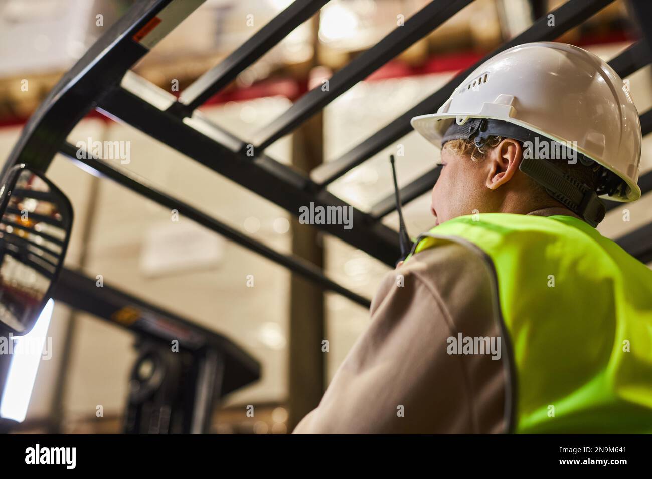 Female worker wearing hardhat while operating forklift truck in