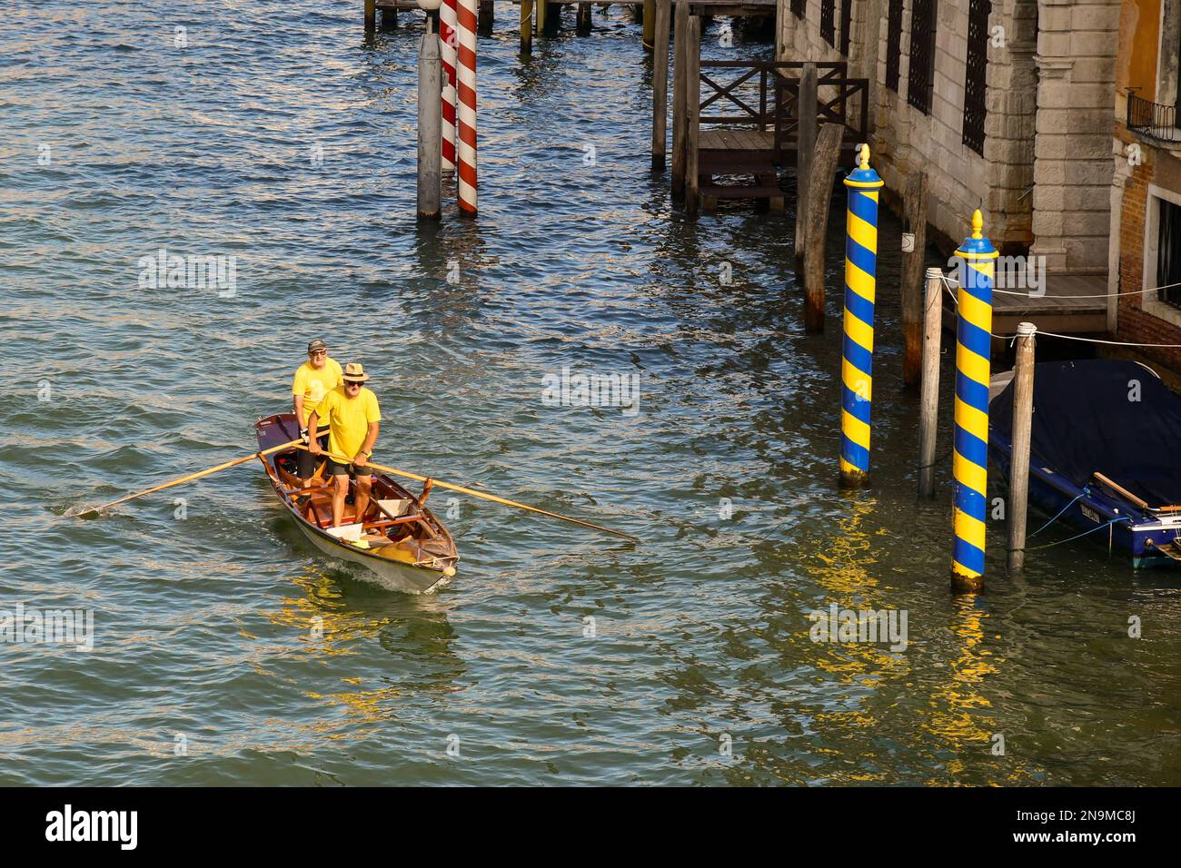 High-angle view of a pair of senior men standing rowing in Venetian row style on the Grand Canal in summer, Venice, Veneto, Italy Stock Photo