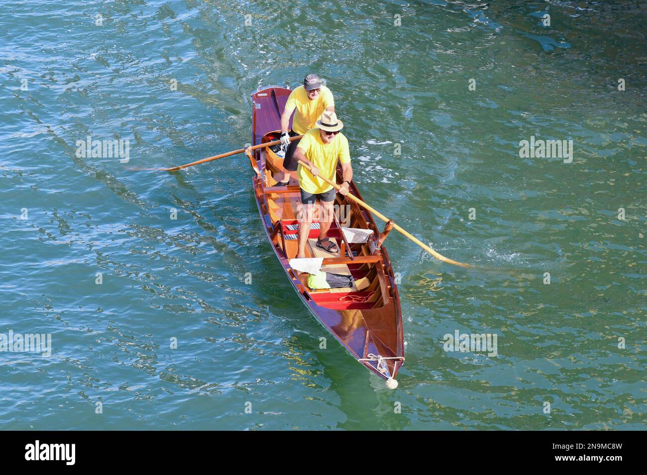 High-angle view of a pair of senior men standing rowing in Venetian row style on the Grand Canal in summer, Venice, Veneto, Italy Stock Photo