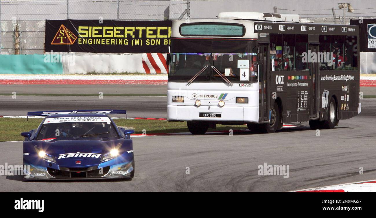 Auto racing fans watch a Super GT race car from a bus during the Super ...