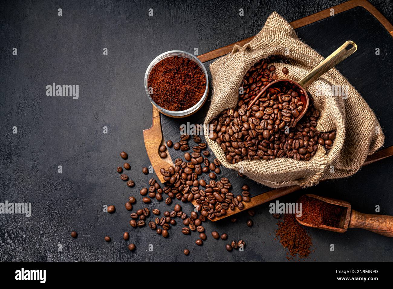 Scoop of coffee beans in a bag on dark board. Top view of ground coffee in a cup and instant