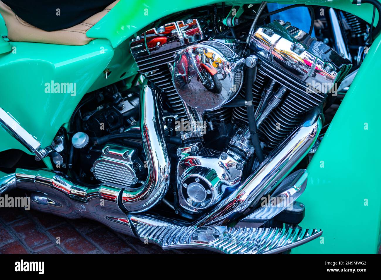 Green motorcycle with a closeup of shiny chrome V-Twin engine that reflects other motorcycles on oil filter Stock Photo