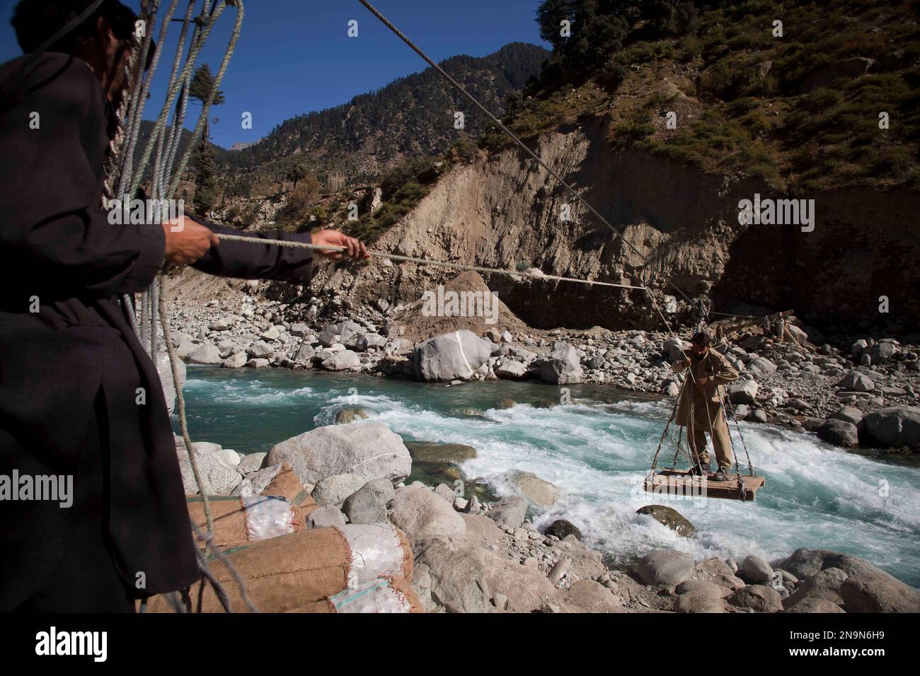 Pakistani villagers use rope trolley to cross the Swat river in Kalam ...