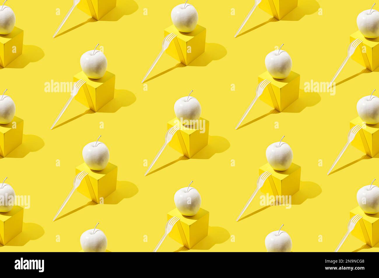 Pattern with white apple on yellow cube-shaped stand and white plastic fork. Stock Photo