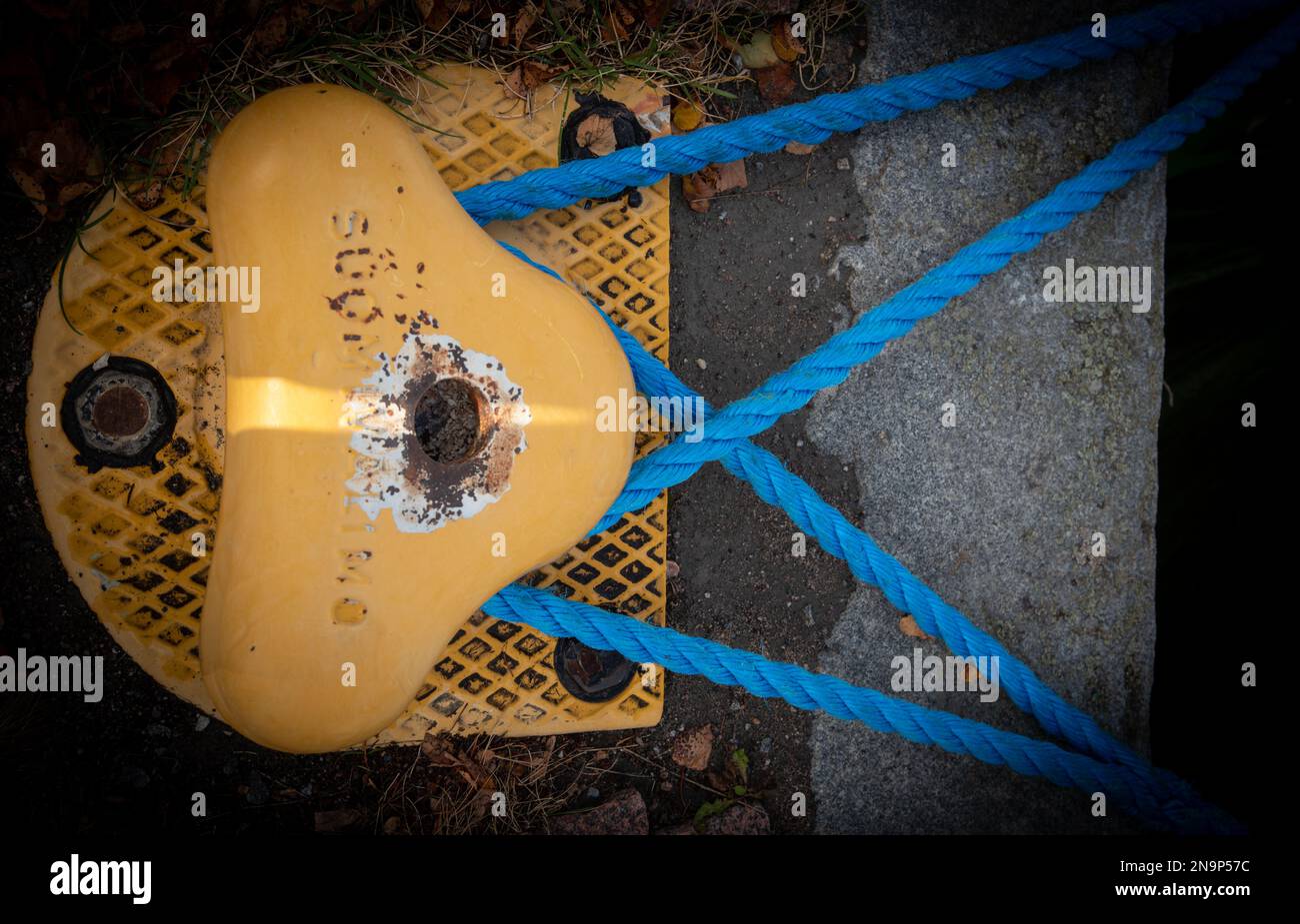 Details of a yellow mooring pole with safety rope for boat support and stability Stock Photo