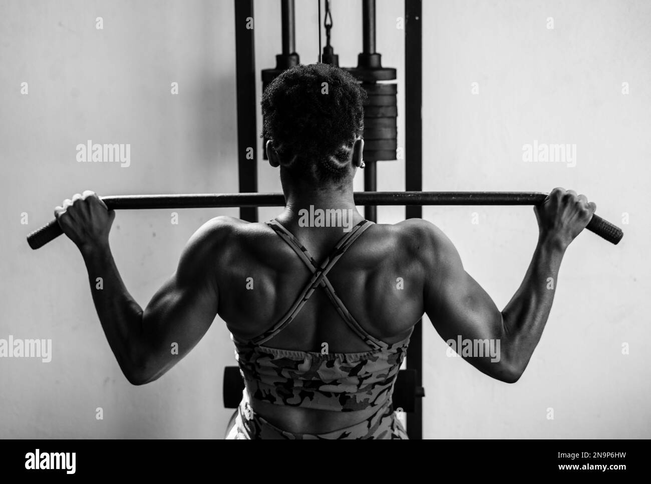 Portrait of muscular woman doing pull-up exercises for back muscles. Health concept. Stock Photo