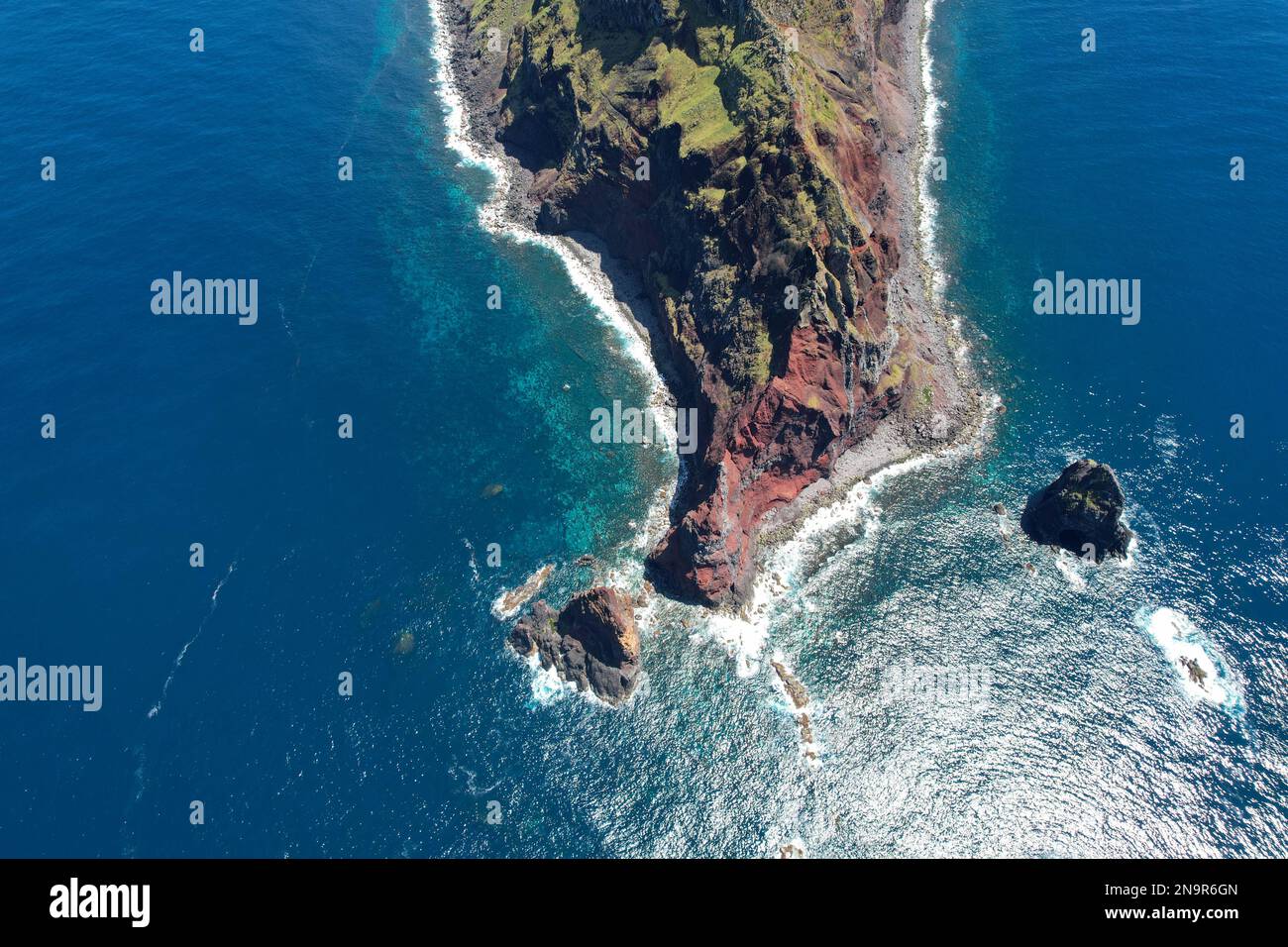 An aerial view of a rocky island in the middle of the sea on a sunny ...