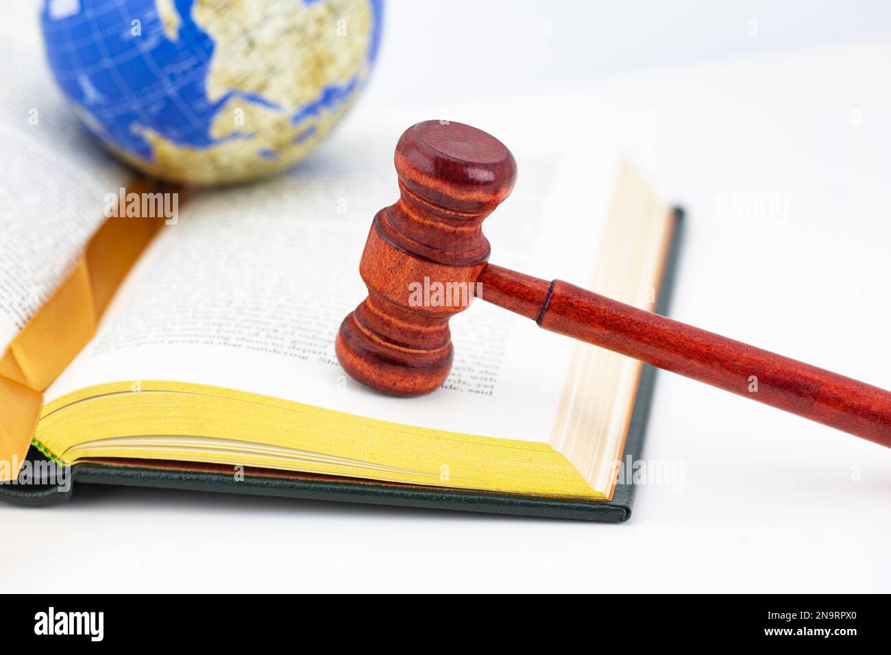 Book with gold edges, wood gavel, and globe placed on white background hold global justice and worldwide equity concepts Stock Photo