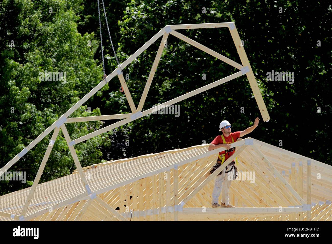 A construction worker is seen installing roofing beams on an industrial ...