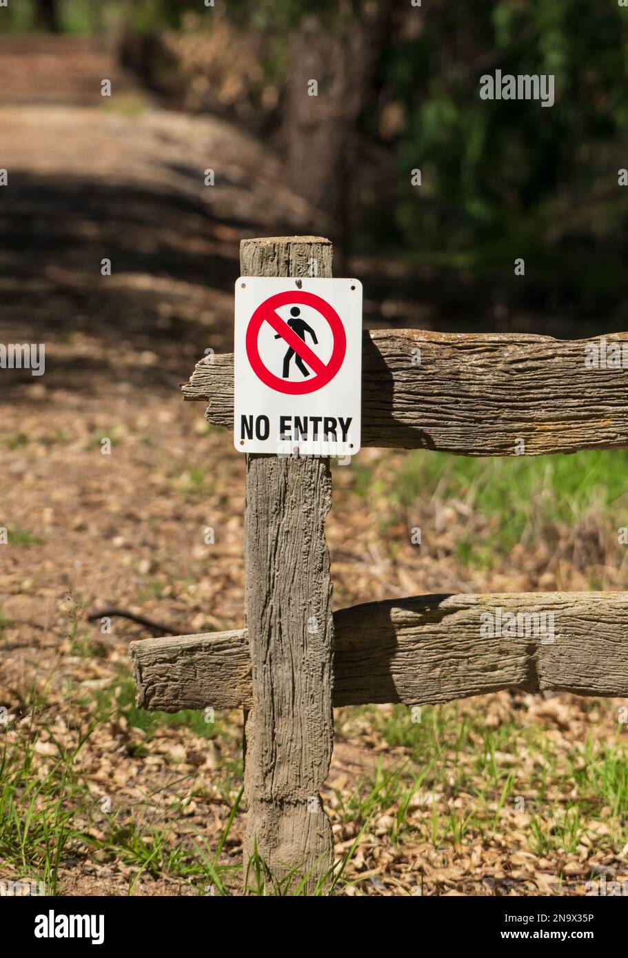 No entry sign on a wooden fence post restricting entry to private land. Stock Photo