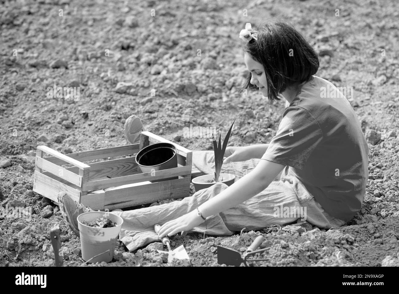 Kid portrait on farmland. I like spending time on farm. Child girl having fun with little shovel and plant in pot. Stock Photo