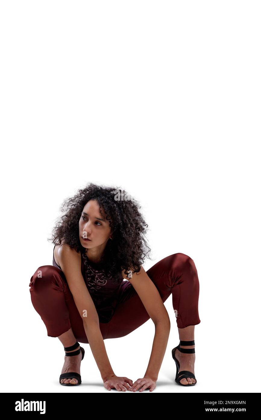 Superhero like Frontal portrait of young curly-haired woman crouched as cat-woman staring at prey in elegant dress of purple and burgundy cloths, her Stock Photo