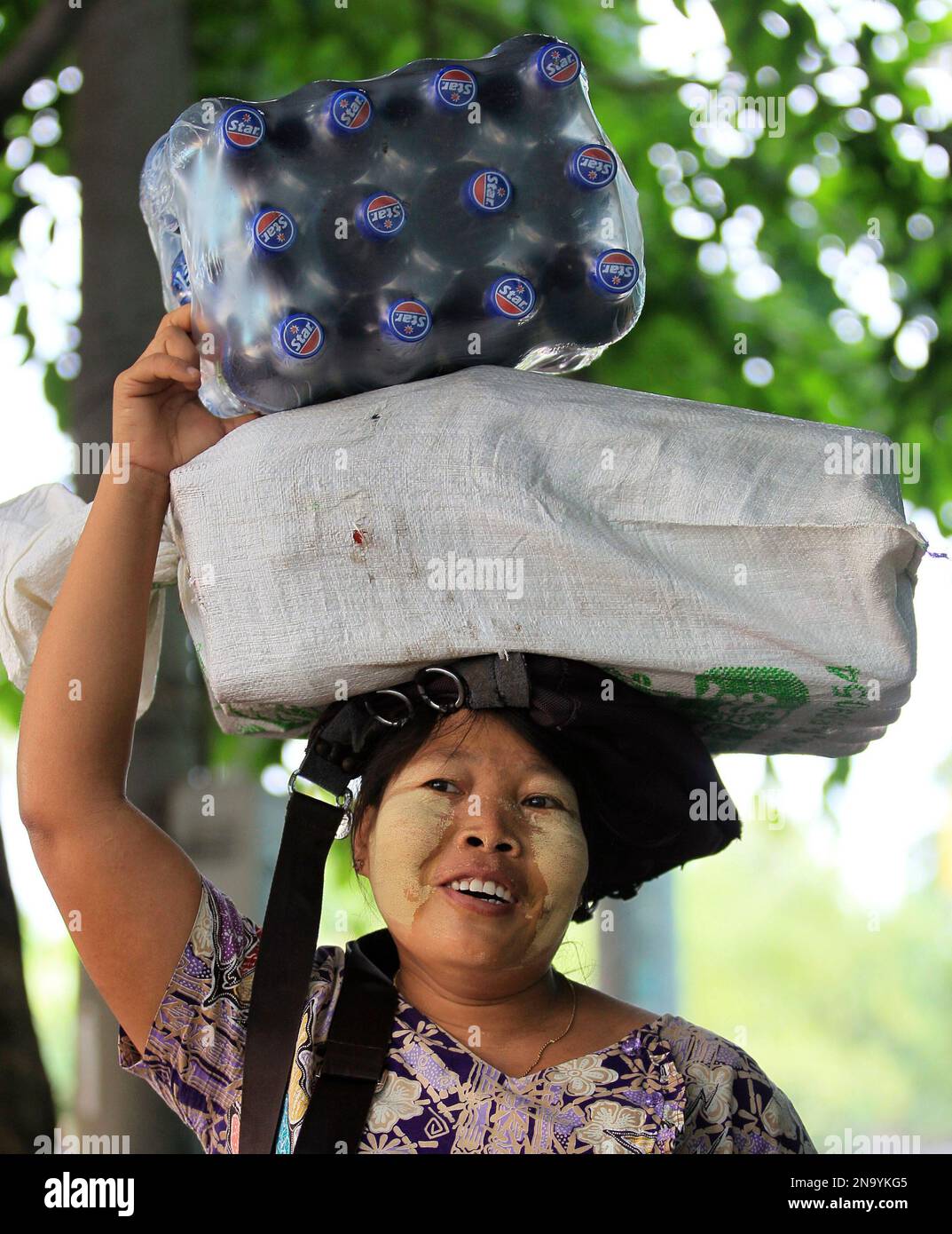 A Myanmar's woman carries the pack of soft drink bottles on the head in Yangon, Myanmar Monday