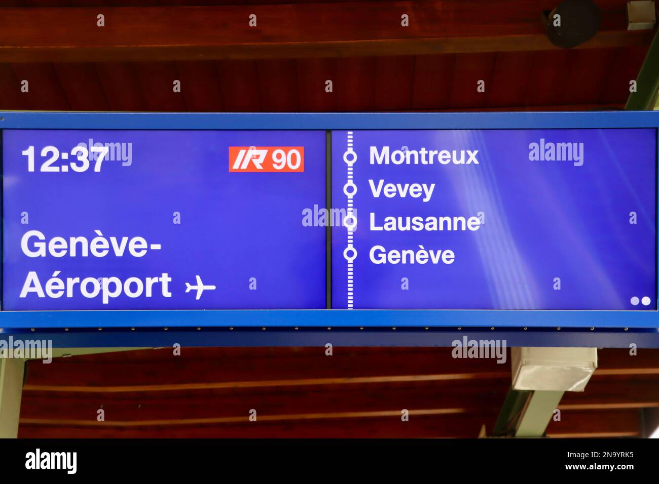 Sign at Aigle railway station for a InterRegio train to Geneva airport with four stops Stock Photo