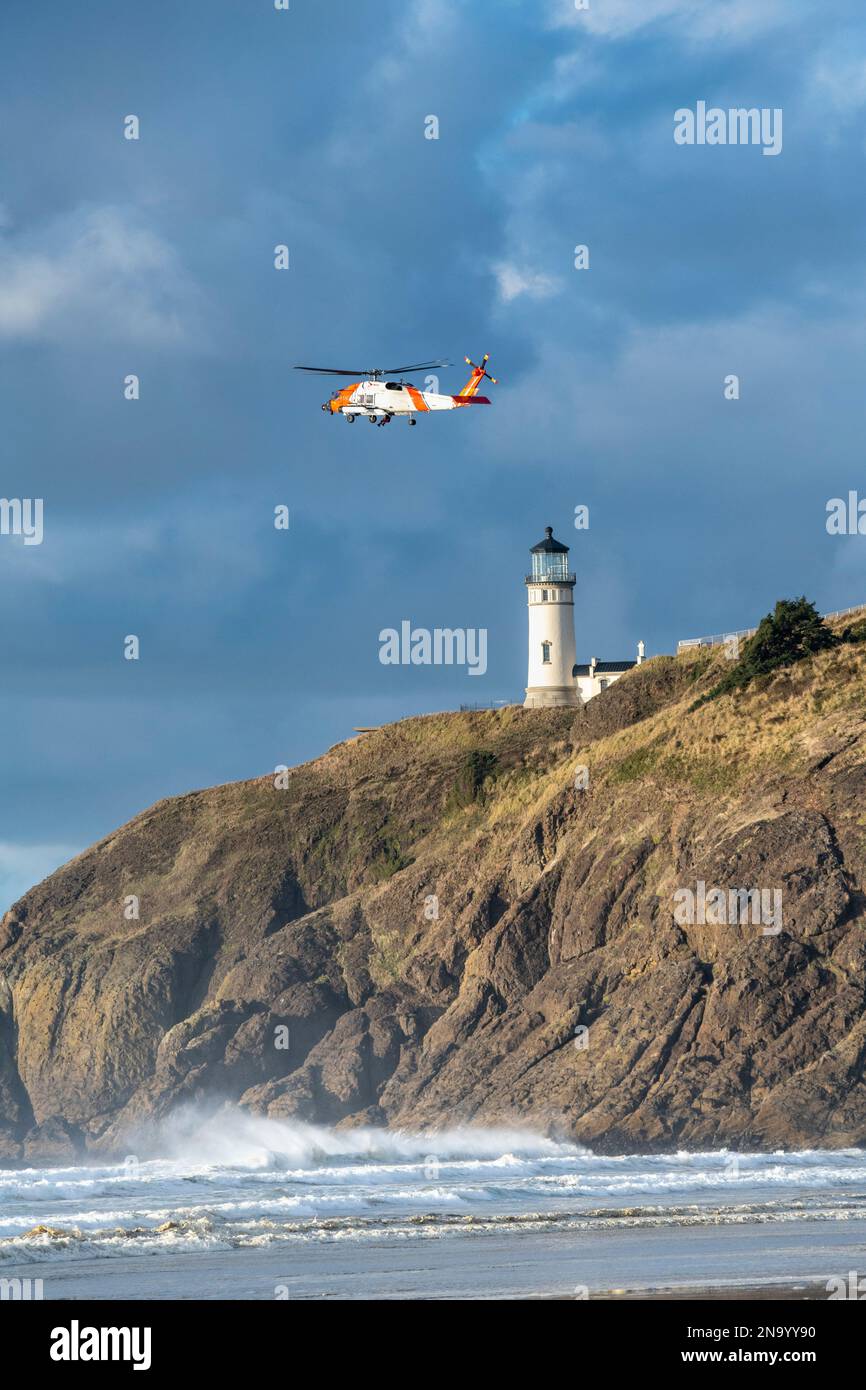US Coast Guard helicopter flying near the Cape Disappointment North Head Lighthouse during a training mission Stock Photo