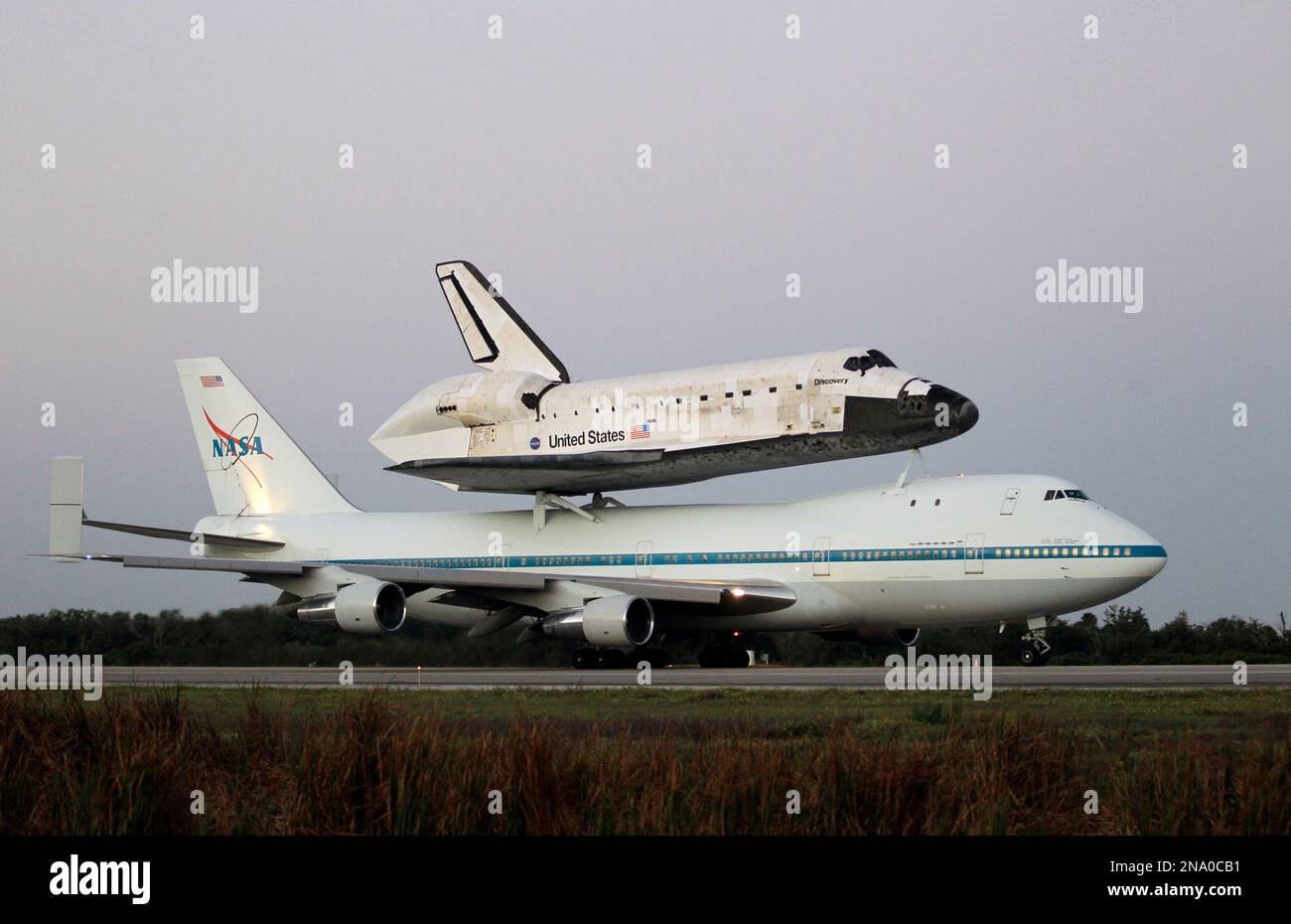 Space shuttle Discovery atop a 747 carrier jet taxi's down the runway ...