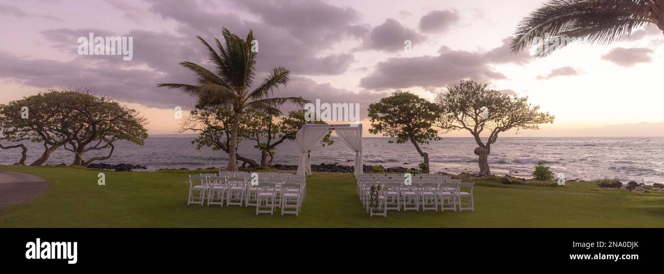 Set-up for an outdoor wedding at sunset along the coast of a hawaiian island with a view of the ocean and horizon Stock Photo