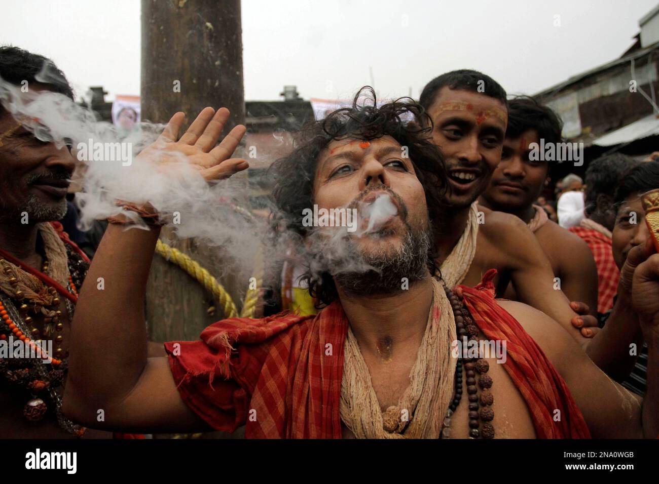 A Hindu devotee of Lord Shiva smokes marijuana prior to a ritual during Shiva Gajan festival in Kolkata, India, Friday, April 13, 2012. Faithful Hindu devotees offer various rituals each year in hope of winning the favor of Hindu god Shiva and ensuring the fulfillment of their wishes. (AP Photo/Bikas Das) Stock Photo