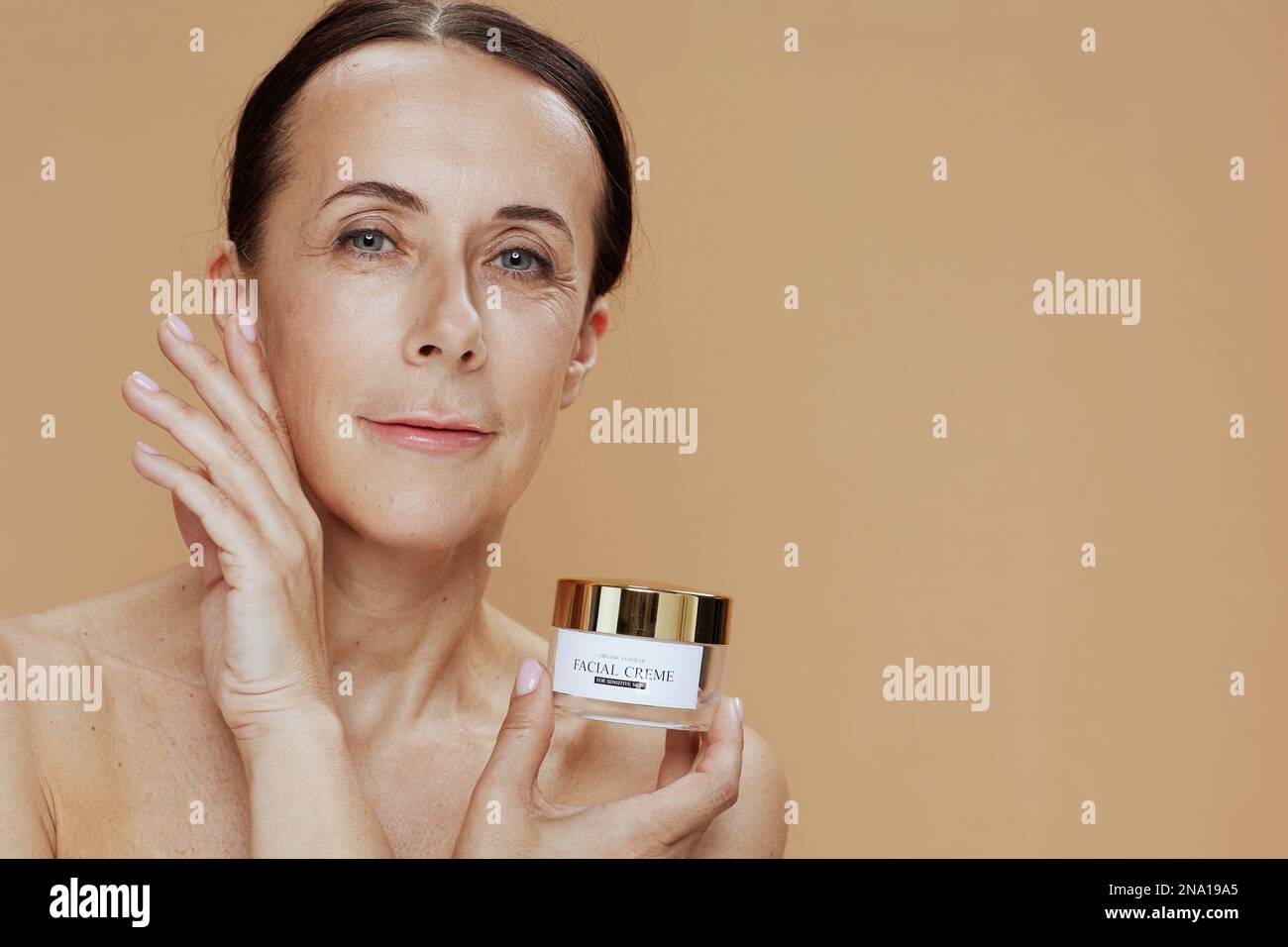 Modern 40 Years Old Woman With Facial Cream Jar Isolated On Beige Stock