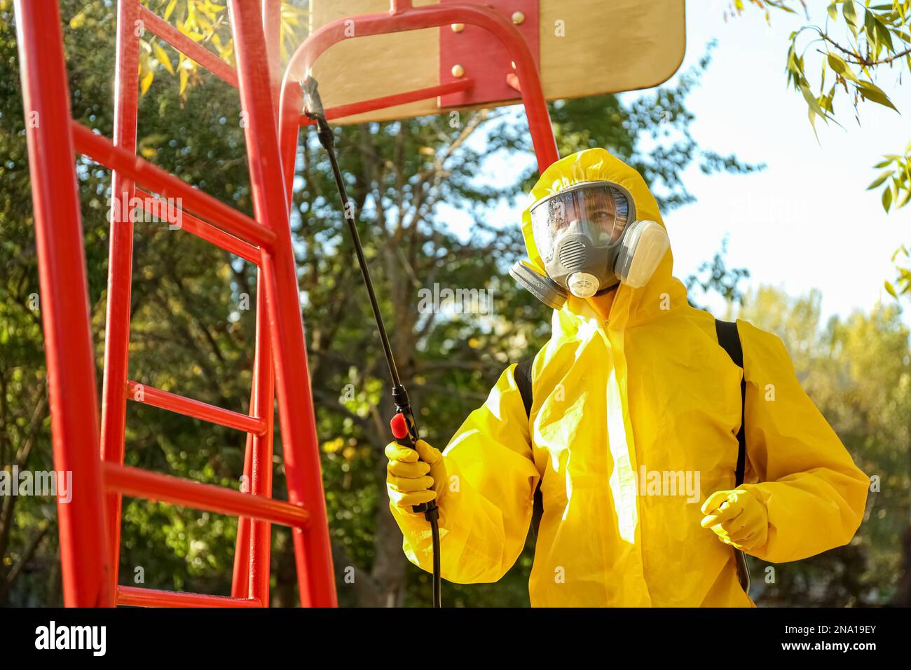 Person in hazmat suit with disinfectant sprayer cleaning children's