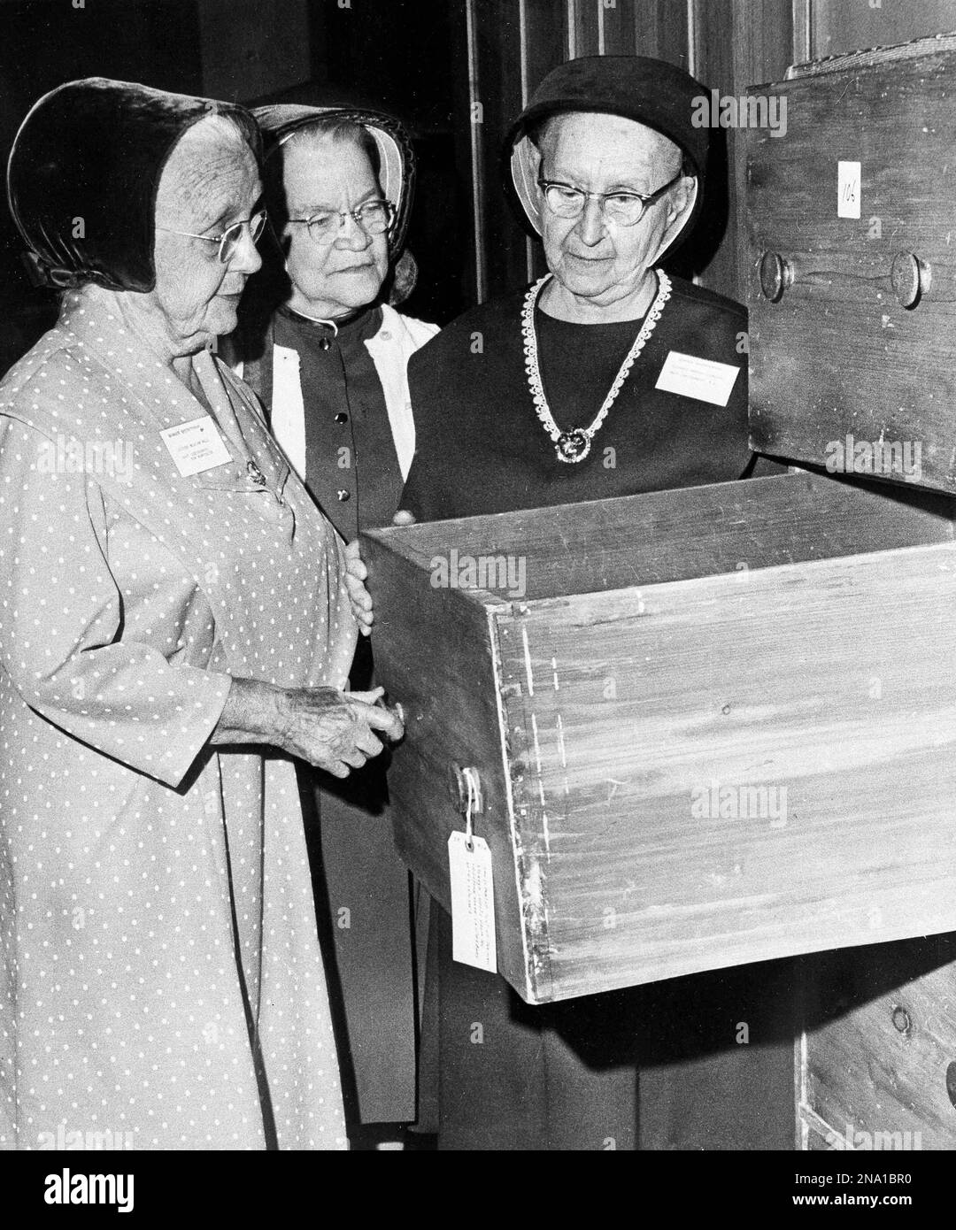 Three members of the Shakers religious sect look at a piece of Shaker