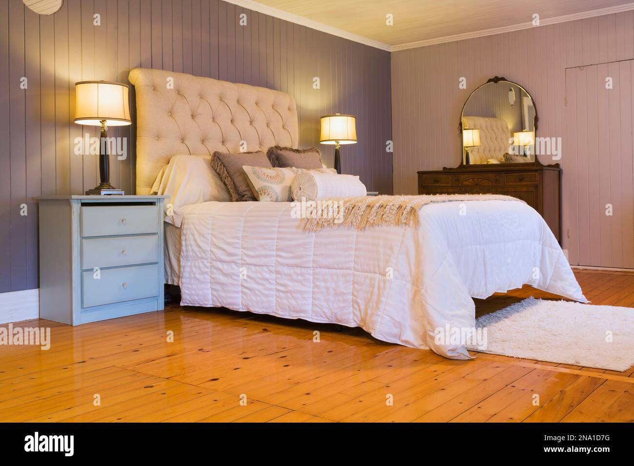 Queen size bed with white bedspread, beige cloth headboard, light blue