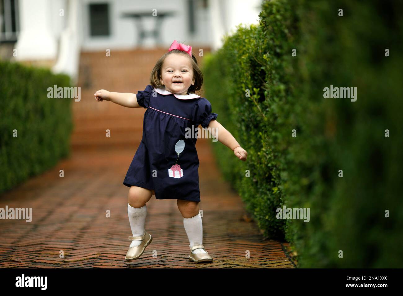 A little girl running down a brick walkway path Stock Photo