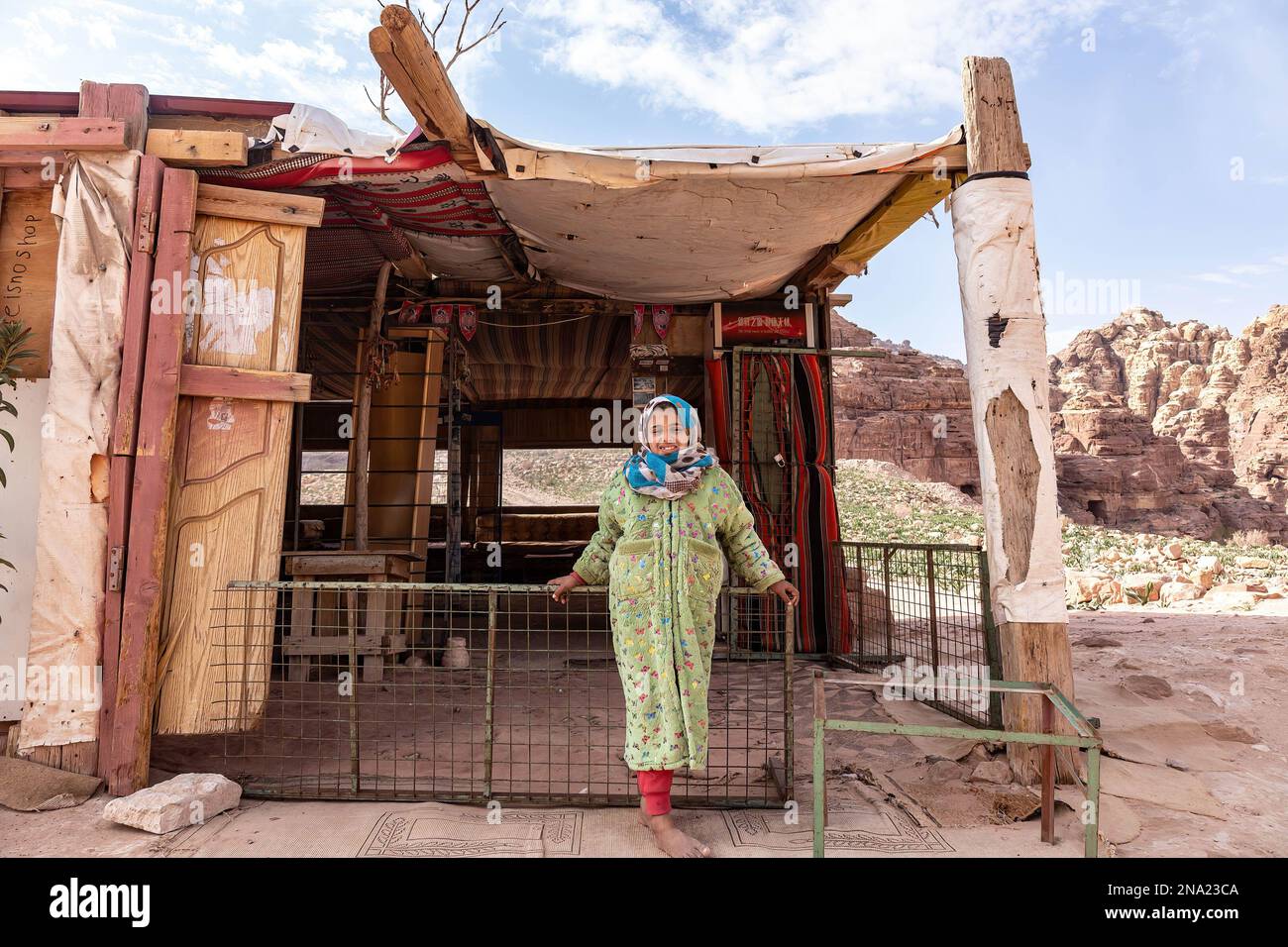 A Bedouine girl stands in front of a hut in Petra, a famous