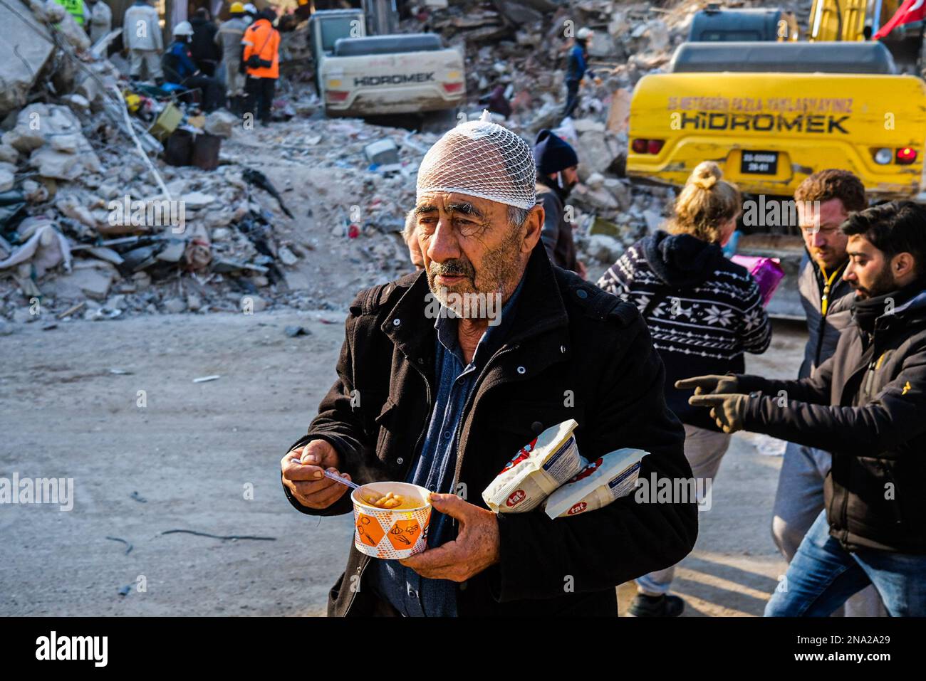 Hatay, Turkey. 12th Feb, 2023. An injured earthquake survivor walks as he eats at the earthquake
