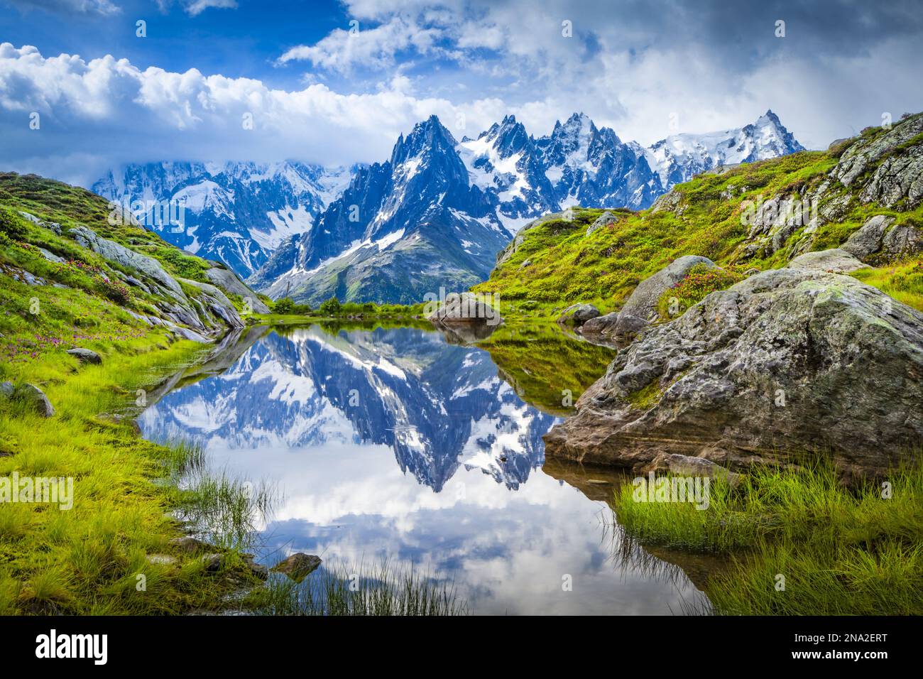 Aiguille des Charmoz, part of Aiguilles de Chamonix, reflects on Lac Flegere surrounded with green meadow, Aiguilles Rouges Stock Photo