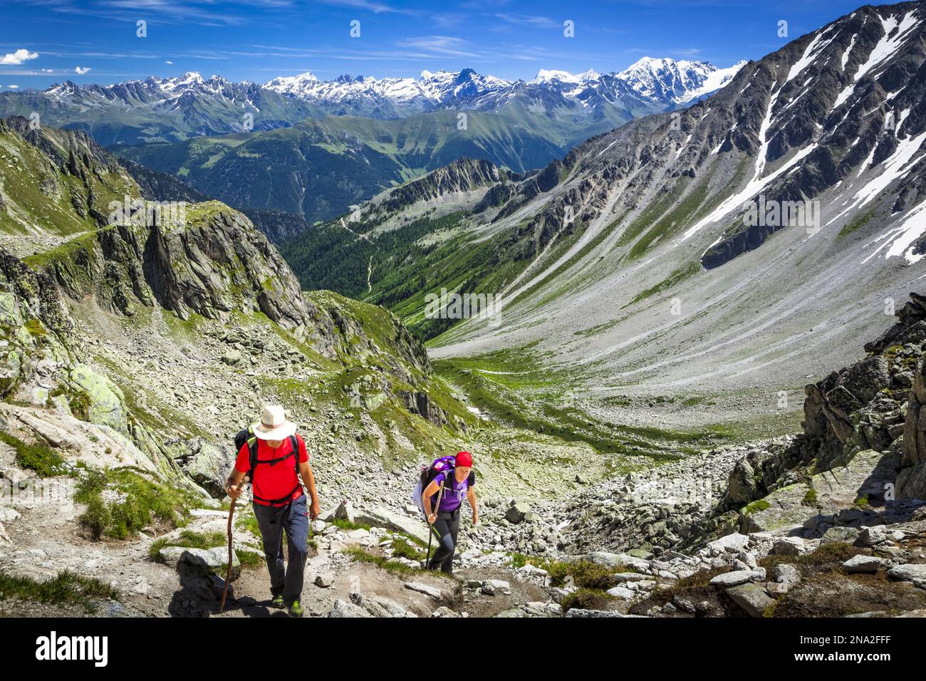Hikers climbing up  the 'Fenetre d'Arpette' mountain pass, Swiss Alps mountains in the background; Trient, Martigny, Switzerland Stock Photo