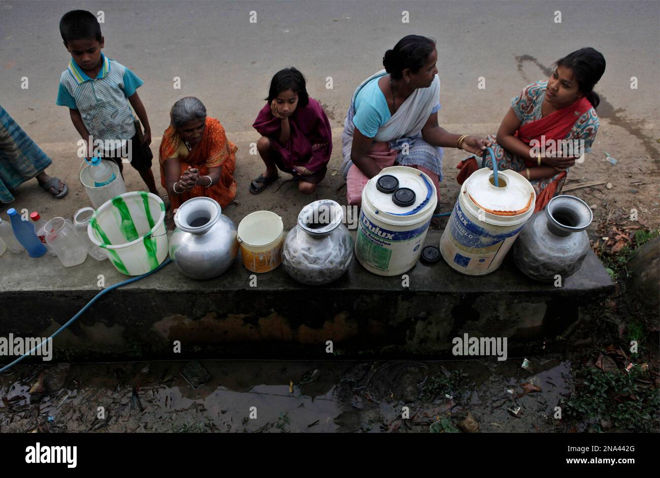 Indian women and children wait in a queue for their turn to collect