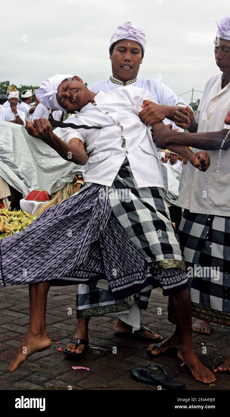 A Balinese man is placed into a trance like state as another points a ...