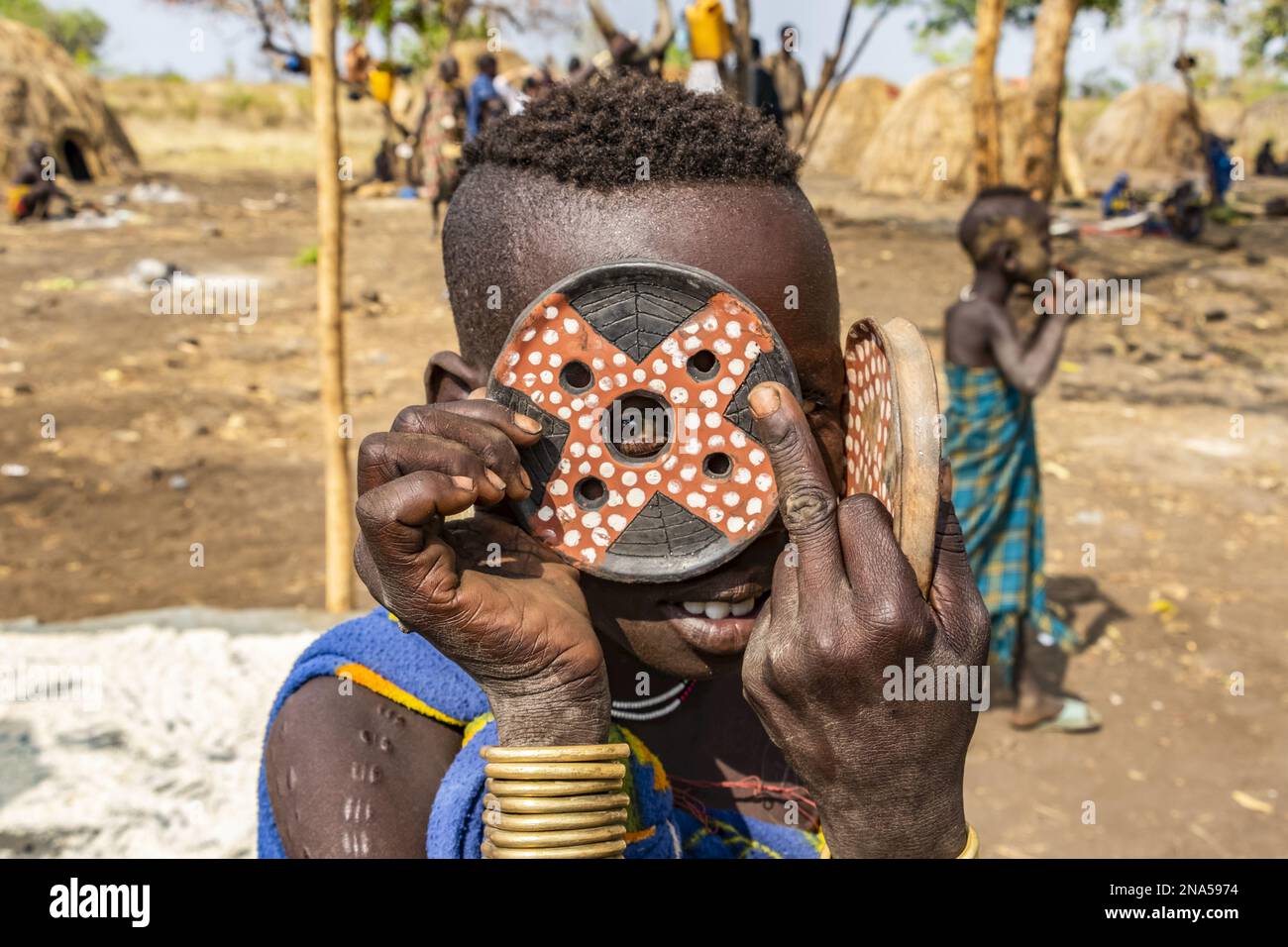 Mursi boy showing a lip plate in a village in Mago National Park; Omo Valley, Ethiopia Stock Photo