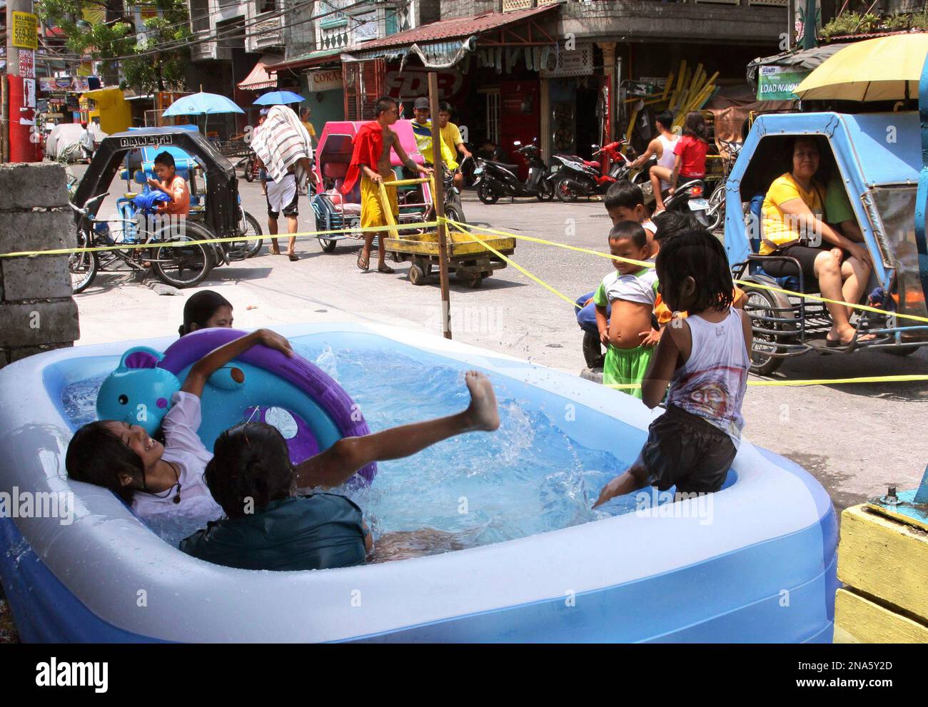 A family enjoy the water in an inflatable pool along the sidewalk to cool  off the summer heat Saturday, March 10, 2012 in Manila, Philippines. (AP  Photo/Pat Roque Stock Photo - Alamy