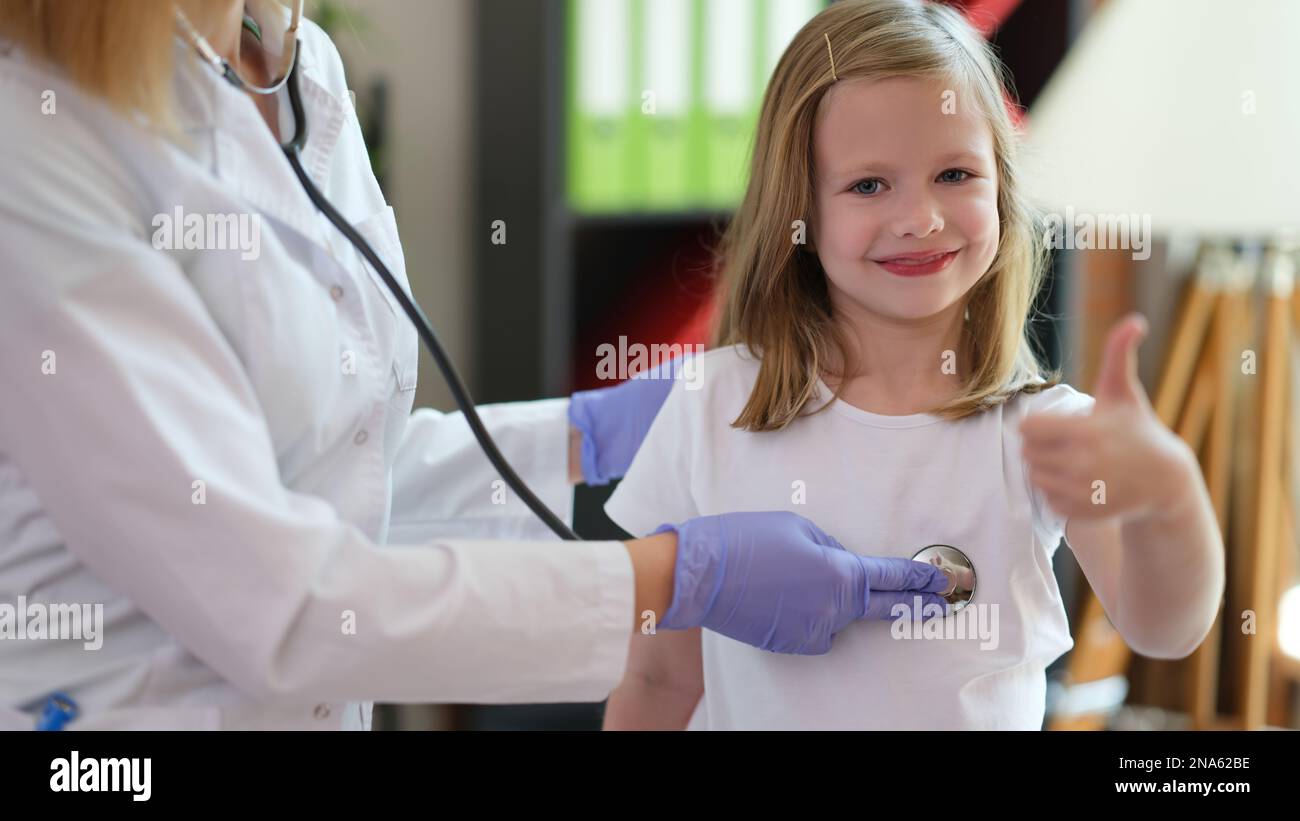 Female doctor examines happy young patient in hospital with stethoscope ...