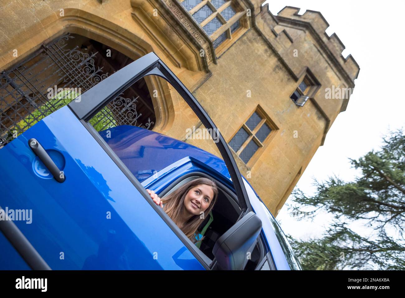 Woman getting out of a camper van in front of Sudeley Castle; Winchcombe, England, UK Stock Photo