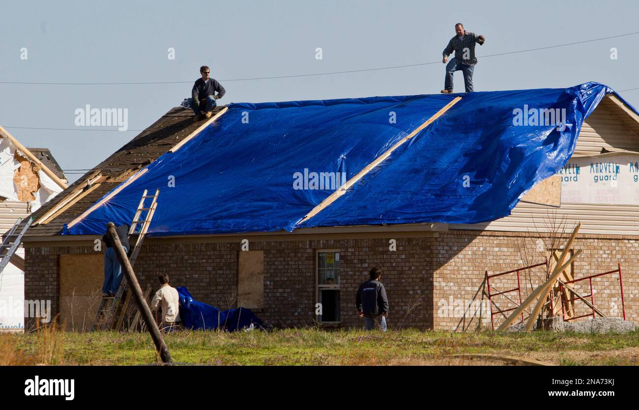 Construction workers tarp a home after a tornado left a path of destruction in the Harvest area on Saturday, March 3, 2012, in Athens, Ala. This home was just rebuilt from an F5 tornado that destroyed it and all the homes on the street on April 27, 2011. Massive thunderstorms, predicted by forecasters for days, threw off dozens of tornadoes as they raced Friday from the Gulf Coast to the Great Lakes. Twisters crushed blocks of homes, knocked out cellphones and landlines, ripped power lines from broken poles and tossed cars, school buses and tractor-trailers onto roads made impassable by debris Stock Photo