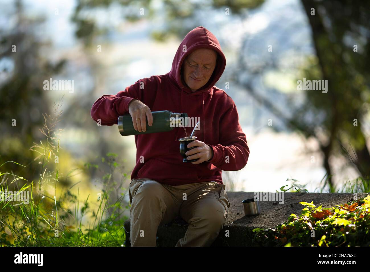 A man pours mate from a thermos into a mug in the park. Stock Photo