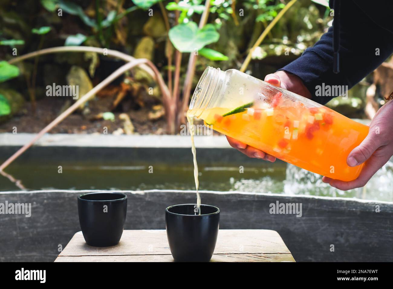 Hands holding bottle with fresh homemade juice made of oranges