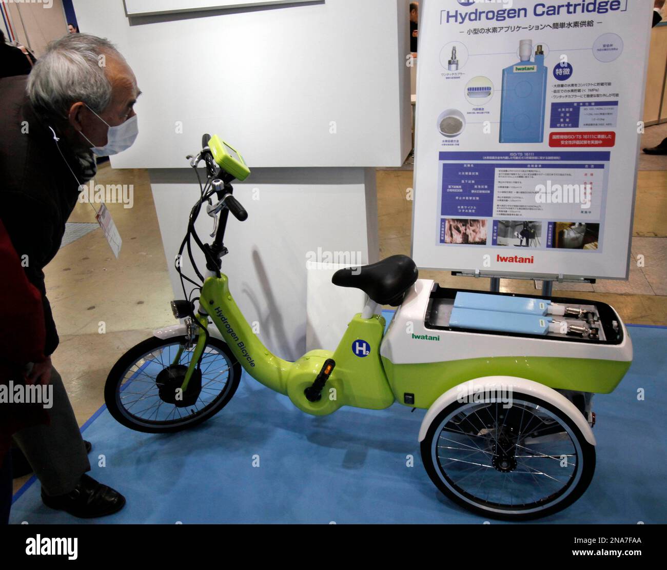 A visitor looks at a hydrogen power-assisted tricycle, exhibited by ...