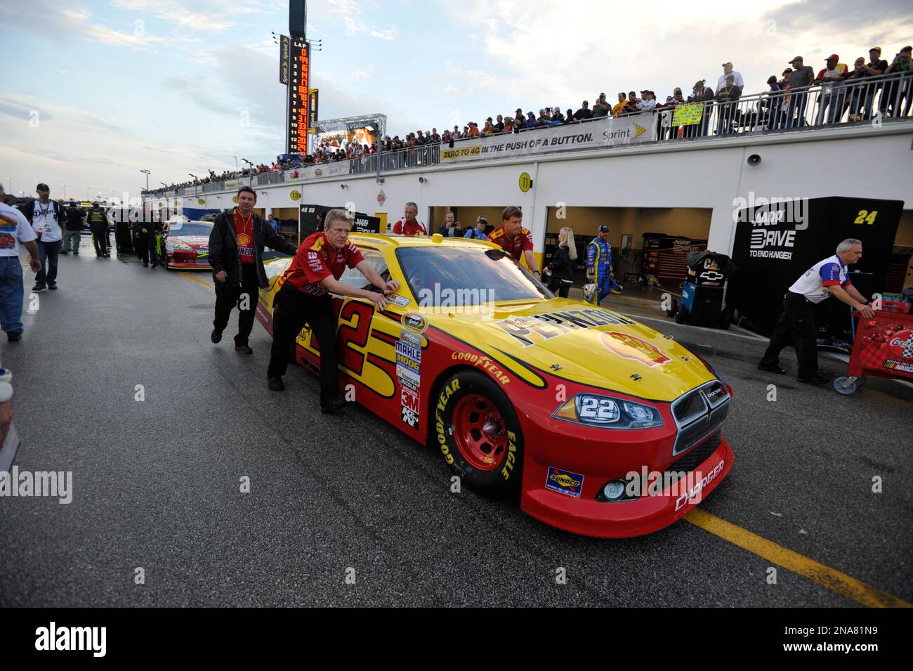Crew members push the car of driver AJ Allmendinger to the starting