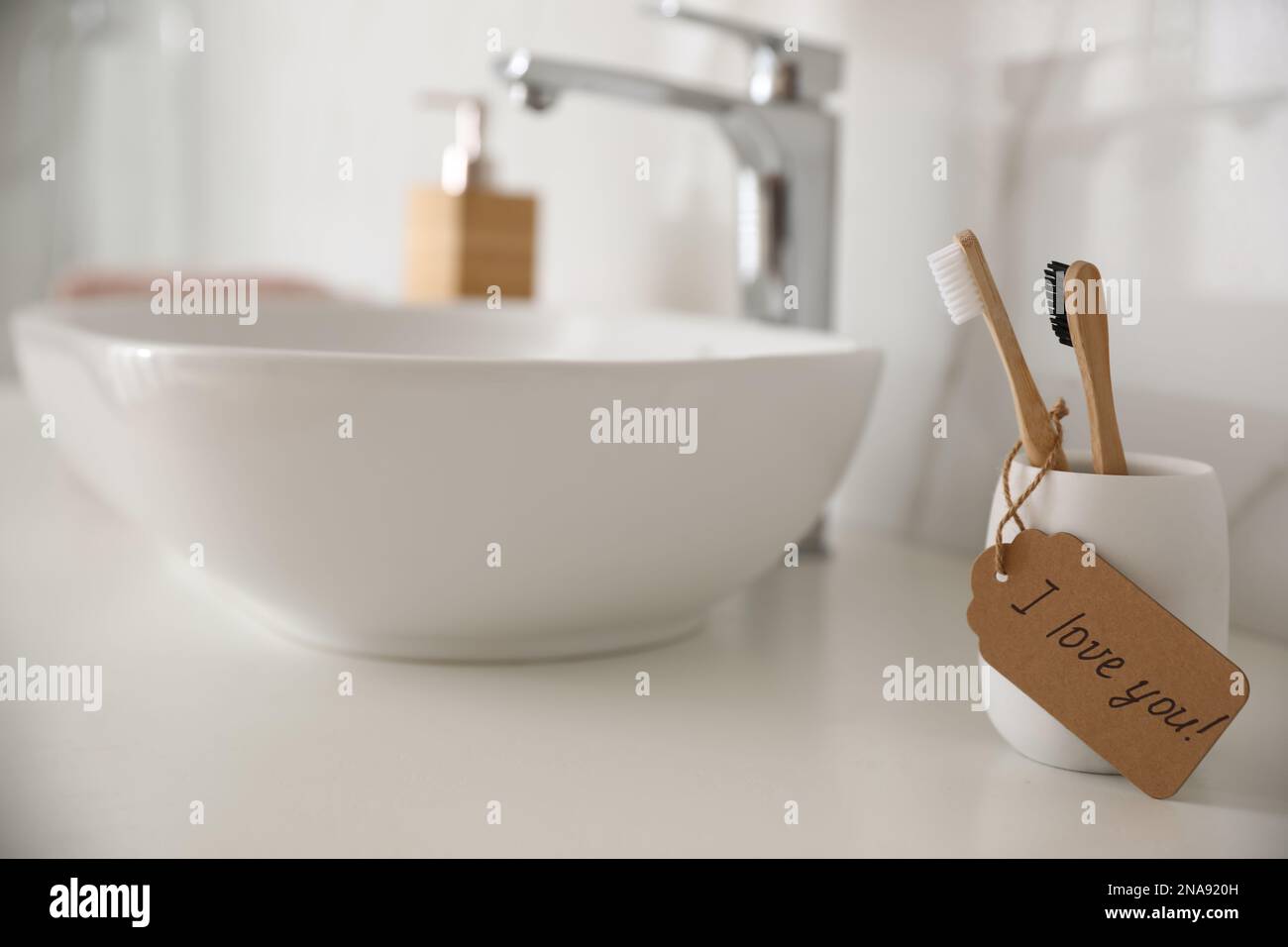 Tag with handwritten text I Love you on toothbrush in bathroom. Romantic message Stock Photo