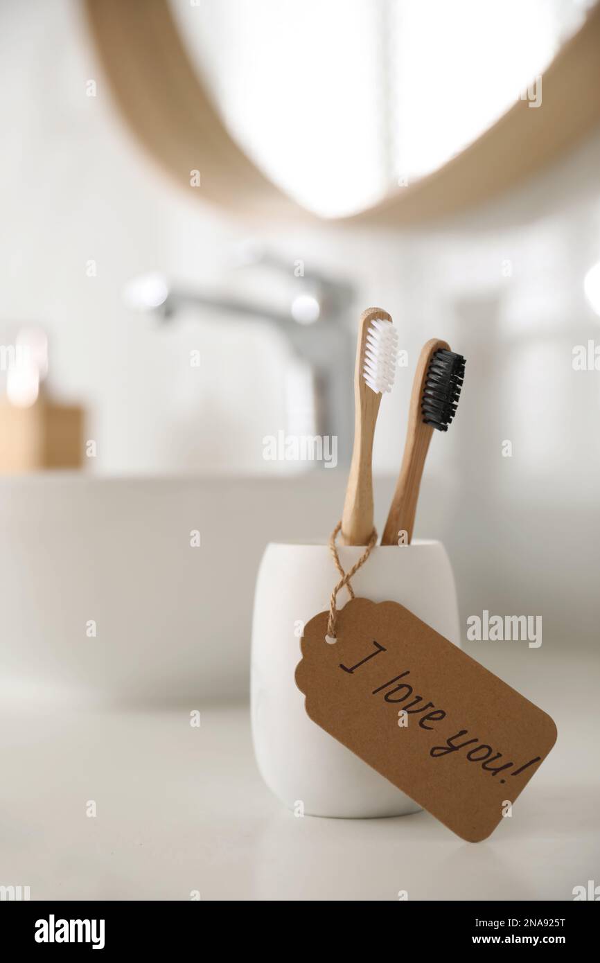 Tag with handwritten text I Love you on toothbrush in bathroom. Romantic message Stock Photo