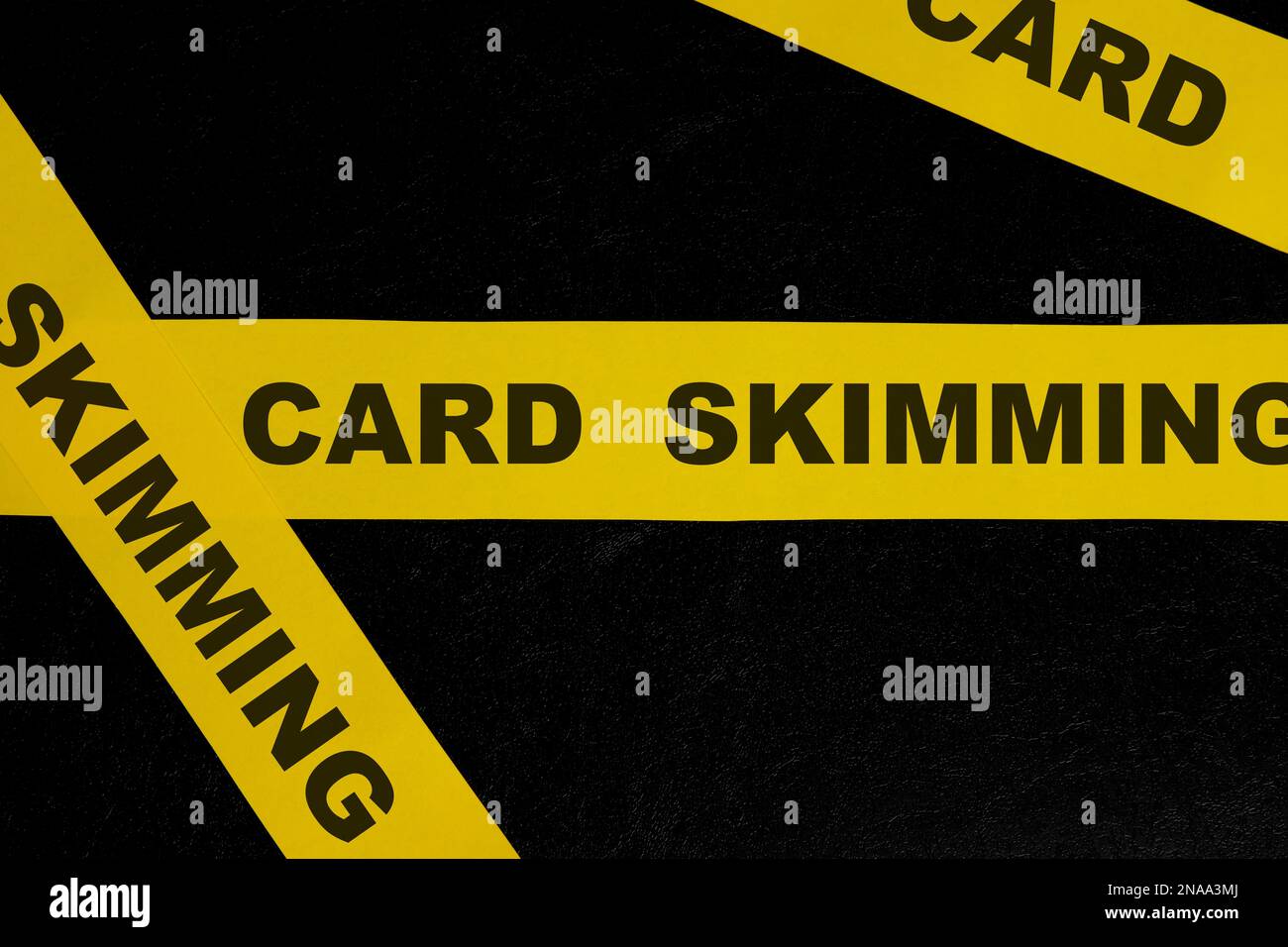 Card skimming cybercrime and theft alert, caution and warning concept. Yellow barricade tape with word in dark black background. Stock Photo