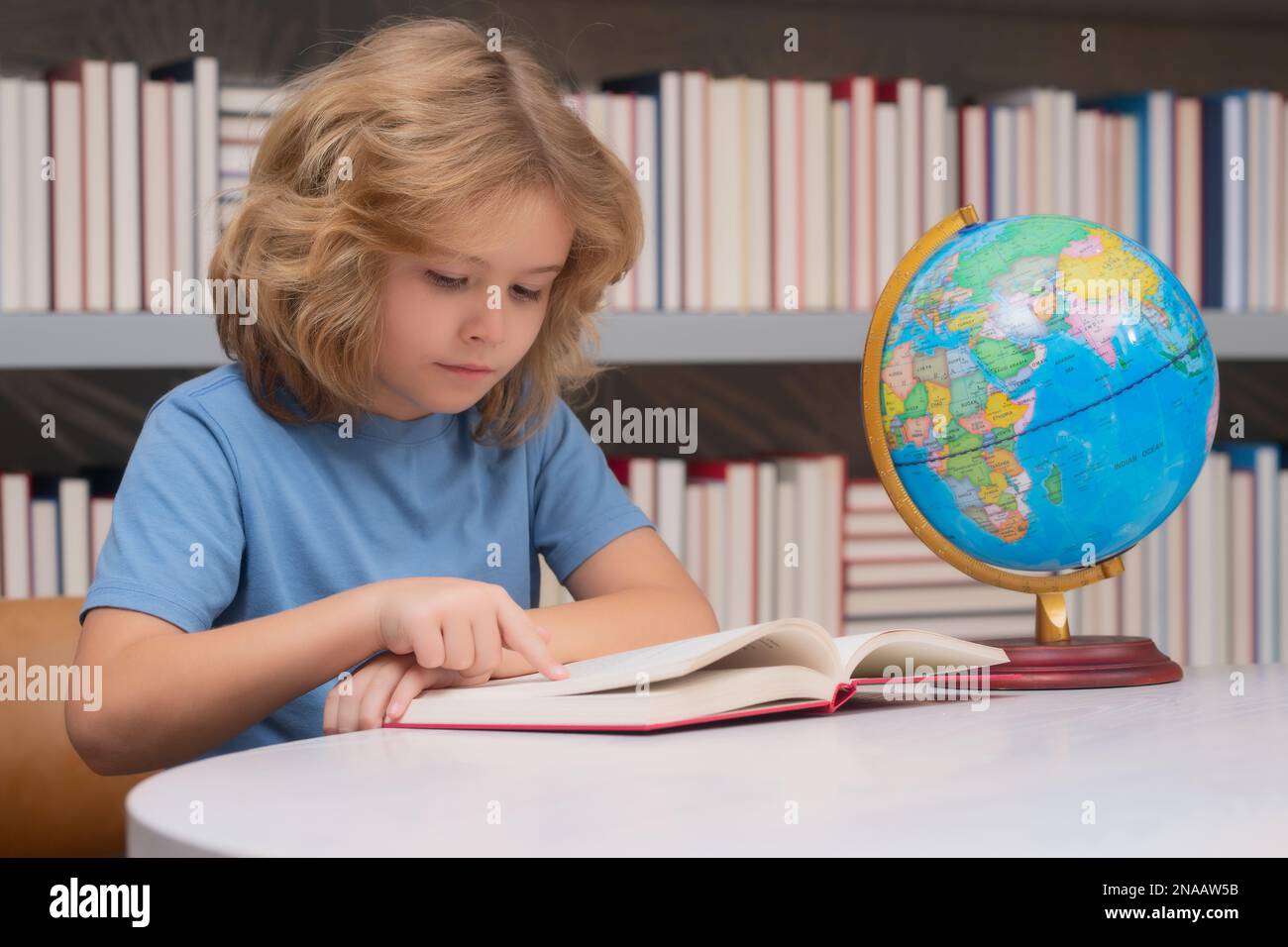 School boy looking at globe in library, geography lesson. School child ...