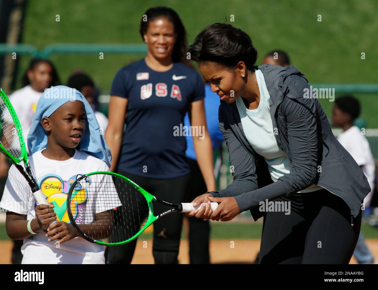 First lady Michelle Obama shows her young tennis partner how to grip a racquet at the ESPN Wide World of Sports Complex at the Walt Disney World Resort, Saturday, Feb
