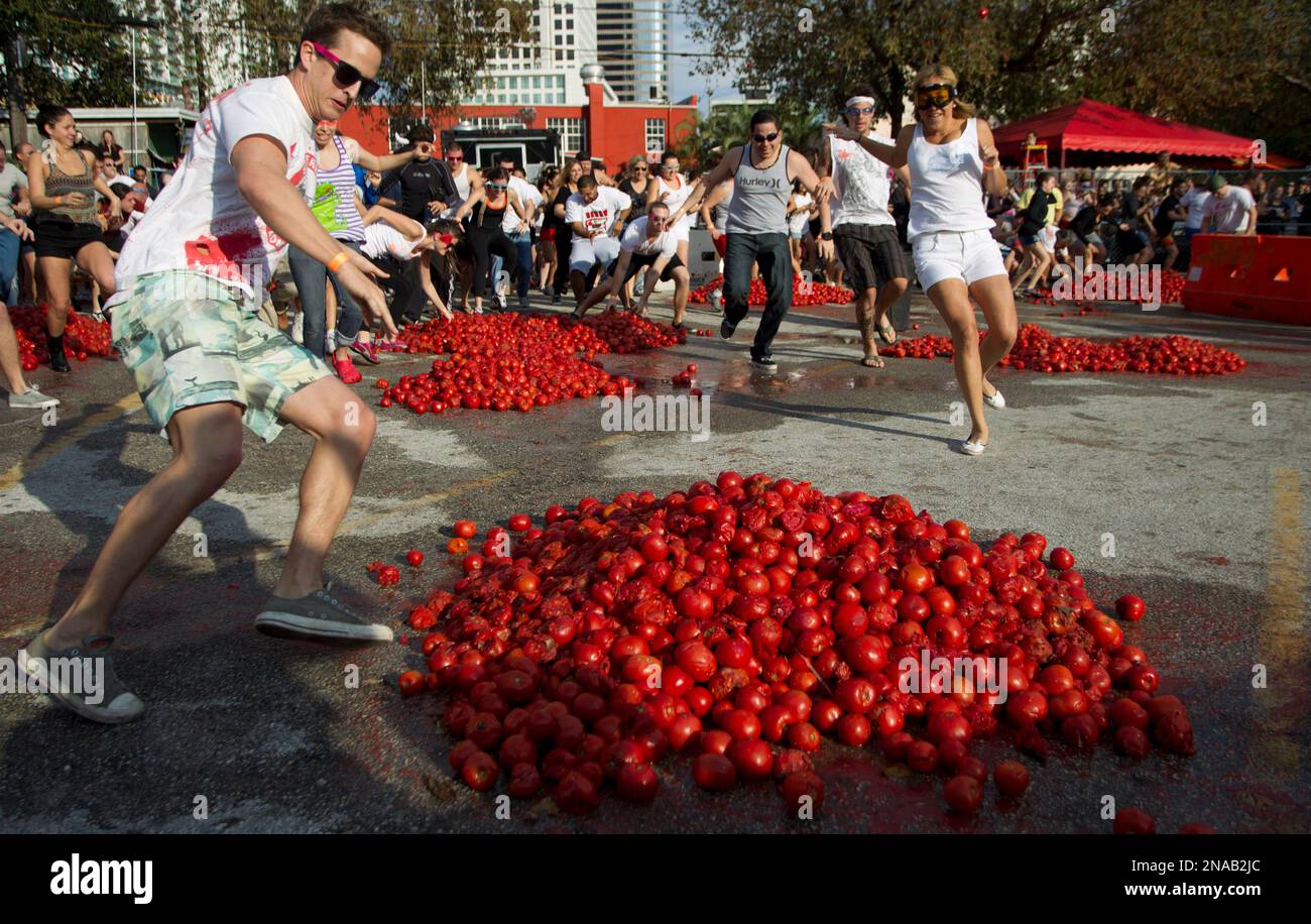People rush towards piles of tomatoes, for a fight, Saturday, Feb. 11, 2012  in Miami. Tobacco Road, Miami's Oldest Bar brought 10,000 Pounds of tomatoes  for Miami's First Tomato Bash. A dump